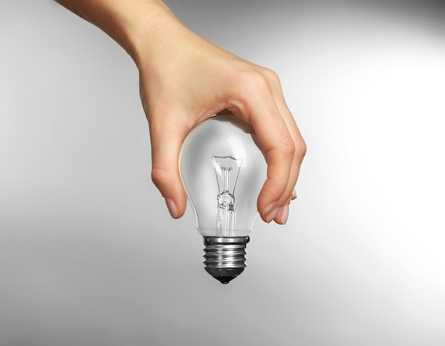 Woman hand holding bulb on grey background