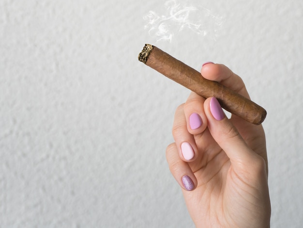 Woman hand holding a burning cigar.