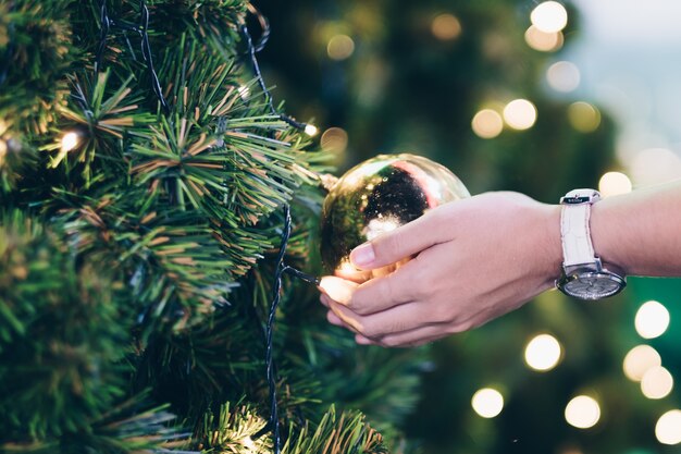 Woman hand holding Christmas decoration, gift box and pine tree branches