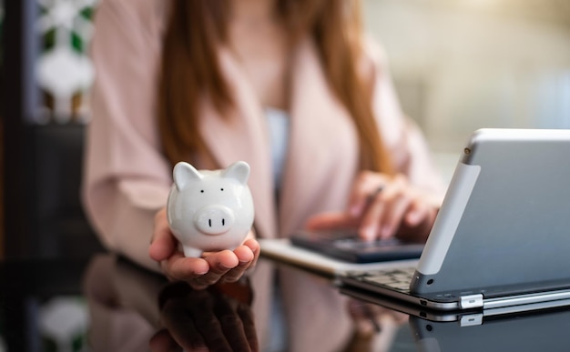 Woman hand holding coin with pig piggy bank Saving and financial accounts conceptxAxA