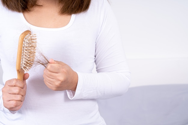 Woman hand holding comb with hair stuck on white background