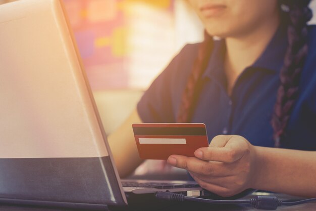 Woman hand holding credit card and using laptop computer.