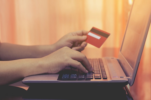 Woman hand holding credit card and using laptop computer. 