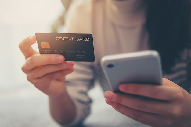 Woman hand holding credit cards and using smartphone for shopping online with payment on internet banking.