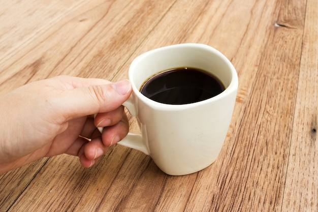 黒いコーヒーのカップを持っている女性の手。