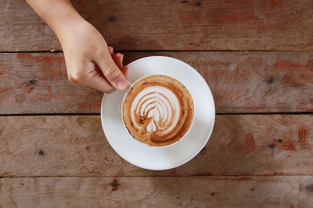 Woman hand holding cup of coffee while resting in the cafe,top view