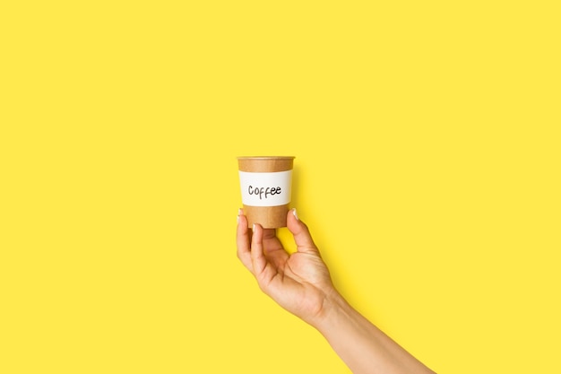 Woman hand holding a disposable paper cup with a coffe sign on a white background with copy space