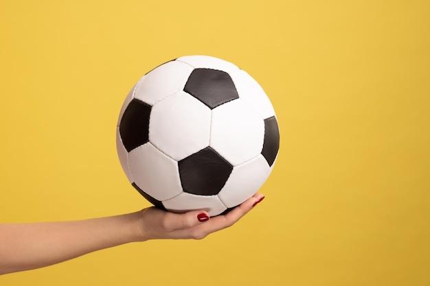 Woman hand holding football or soccer ball supporting favorite football team on match