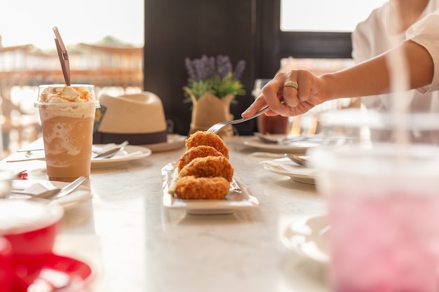 Woman hand holding fork  taking food with drink on table.