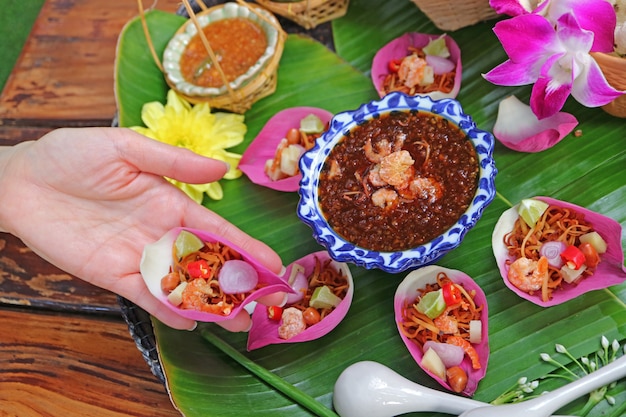 여자가 손을 잡고 신선한 연꽃 꽃잎 짭짤한 래핑 된 Miang kham 태국어