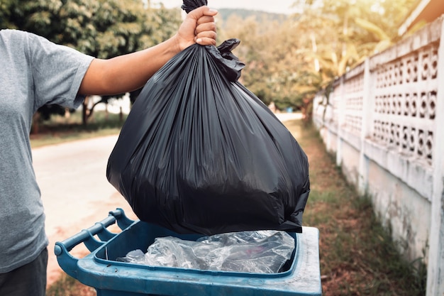 Woman hand holding garbage in black bag for cleaning in to\
trash