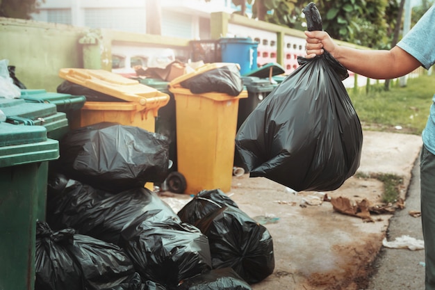 Woman hand holding garbage in black bag for cleaning in to trash