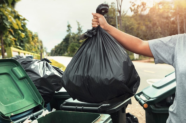Photo woman hand holding garbage in black bag for cleaning in to trash