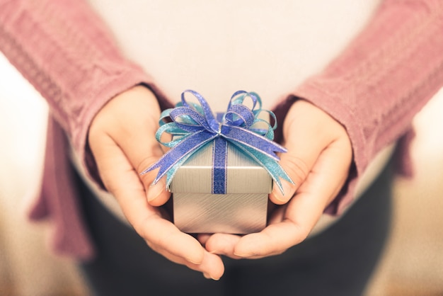 Woman hand holding gift box of christmas present.