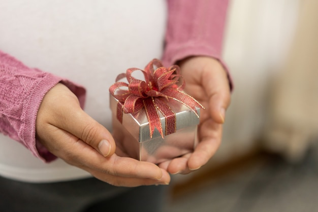 クリスマスプレゼントのギフトボックスを持つ女性の手。