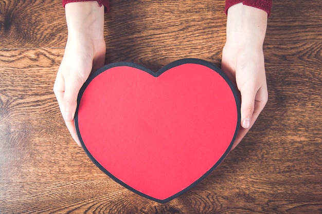 Woman hand holding gift box heart