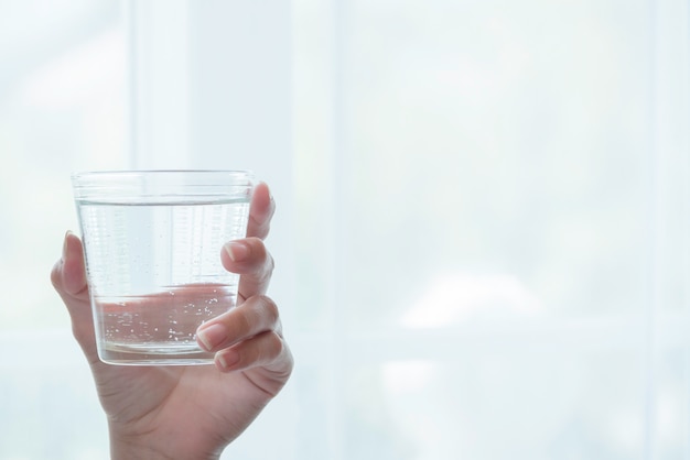 Mano di donna che tiene un bicchiere con acqua