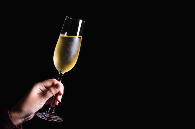 Woman hand holding glasses of champagne on the black background