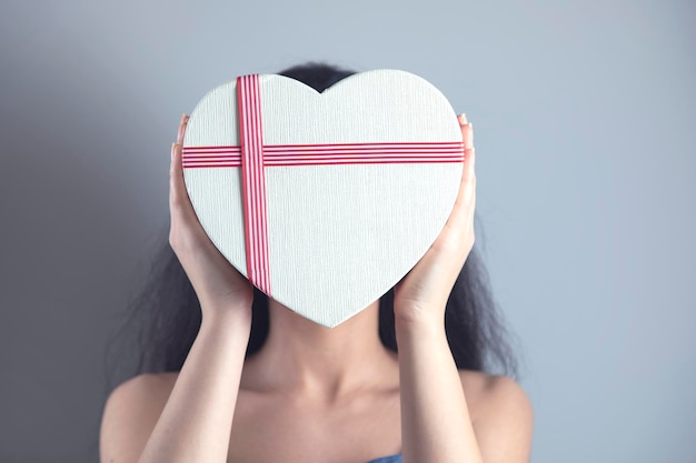 Woman hand holding heart box in face