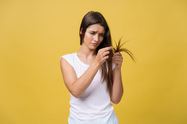 ヘアケアの問題の損傷した分割端を見ながら彼女の長い髪を持っている女性の手。