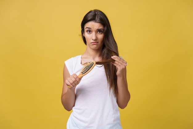 Woman hand holding her long hair with looking at damaged splitting ends of hair