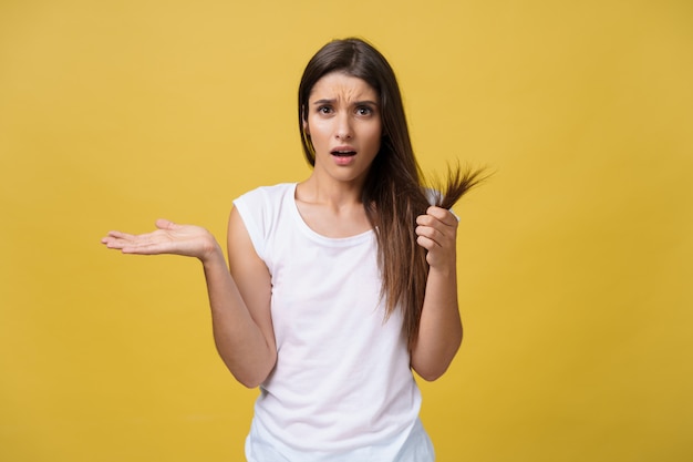 Woman hand holding her long hair with looking at damaged splitting ends 