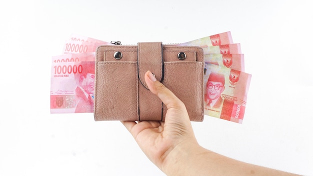 Woman hand holding her wallet full of money isolated on white background Finances and money concept 100000 IDR Indonesia Currency