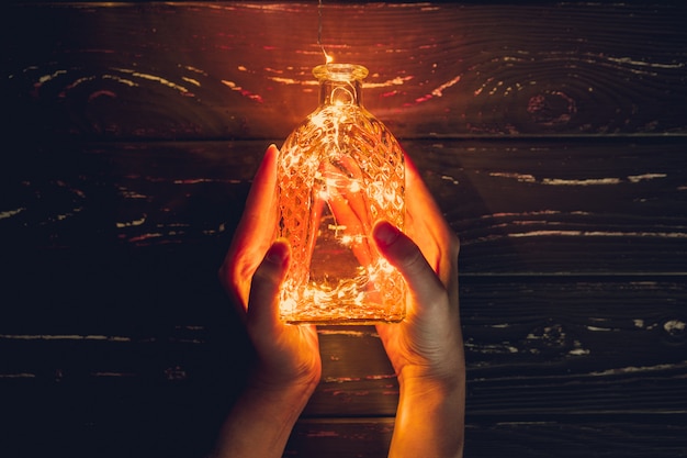 Woman hand holding illuminated garland in her hands in dark