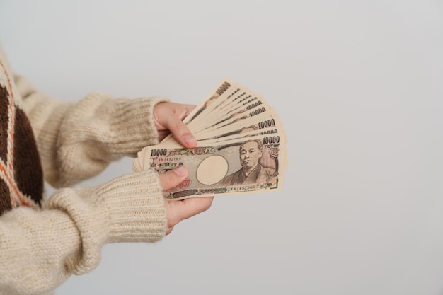 Женщина держит стопку банкнот японской иены деньги в тысячу иен япония наличные налоговый спад экономика инфляция инвестиционное финансирование и концепции оплаты покупок