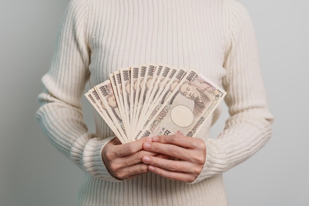 Woman hand holding Japanese Yen banknote stack Thousand Yen money Japan cash Tax Recession Economy Inflation Investment finance and shopping payment concepts