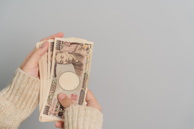 Woman hand holding Japanese Yen banknote stack Thousand Yen money Japan cash Tax Recession Economy Inflation Investment finance and shopping payment concepts