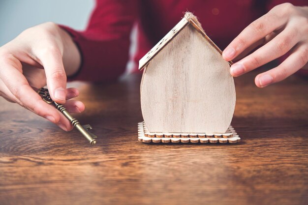 Woman hand holding key with house model