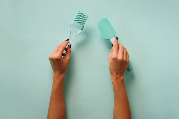 Woman hand holding kitchen utensils on blue background. 