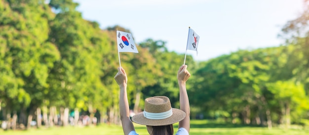 자연 배경에 한국 국기를 들고 여자 손입니다. 건국, 개천절, 공휴일, 광복절 및 행복한 축하 컨셉