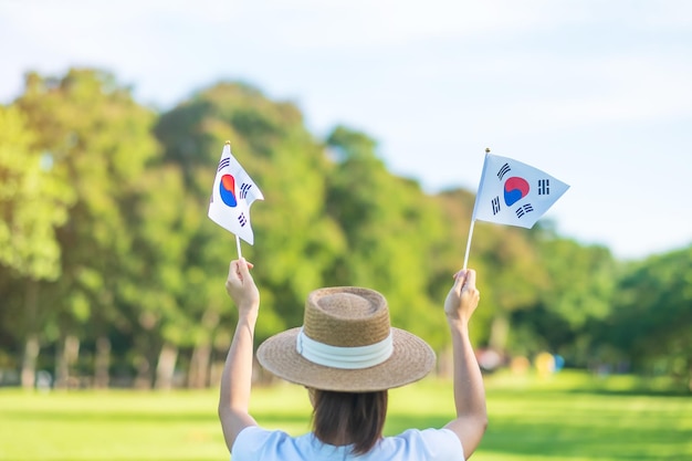 Woman hand holding Korea flag on nature background National Foundation Gaecheonjeol public Nation holiday National Liberation Day of Korea and happy celebration concepts