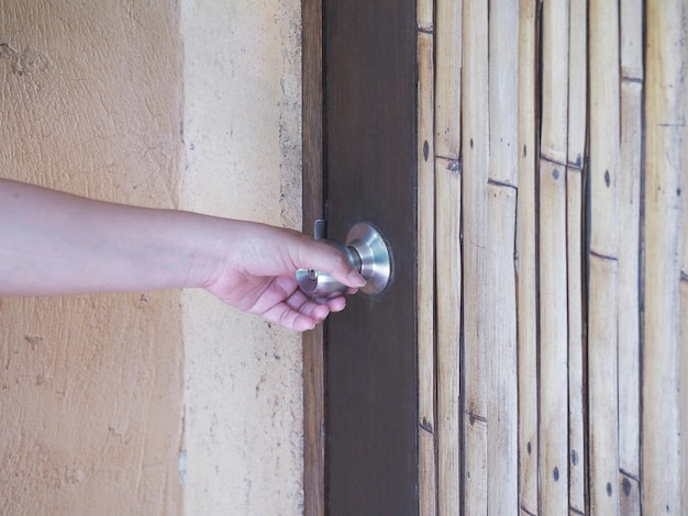 Woman hand holding metal vintage knob and opening wooden door