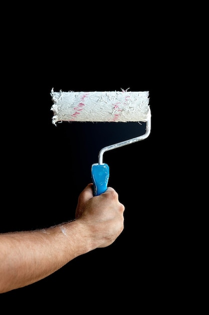 Woman hand holding a paint roller on a black background