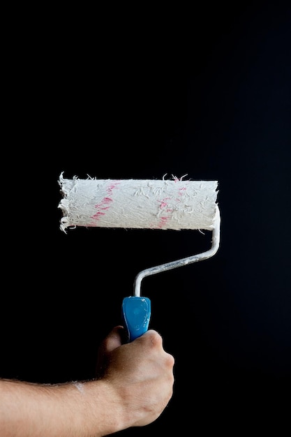 Woman hand holding a paint roller on a black background