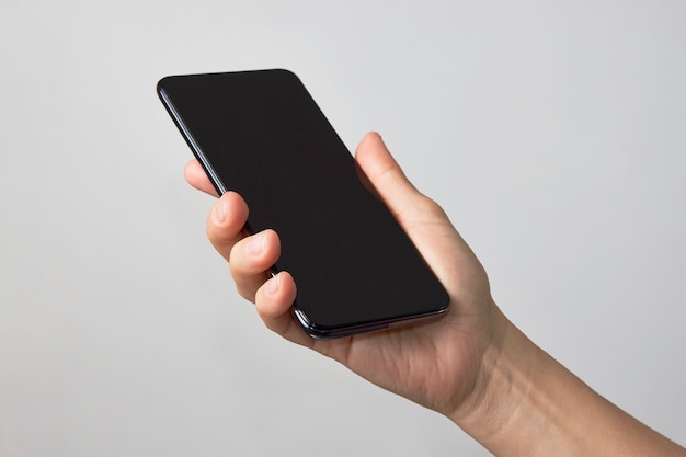 Woman hand holding phone on white background with copy space