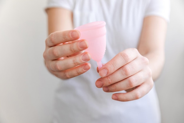 Woman hand holding pink menstrual cup isolated on white background. Woman modern alternative eco gynecological hygiene in menstruation period. Container for blood in girl hand.