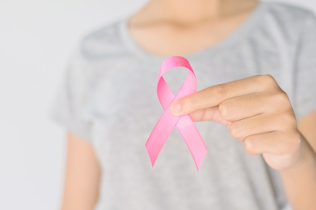 Woman hand holding pink ribbon breast cancer awareness. concept healthcare and medicine 