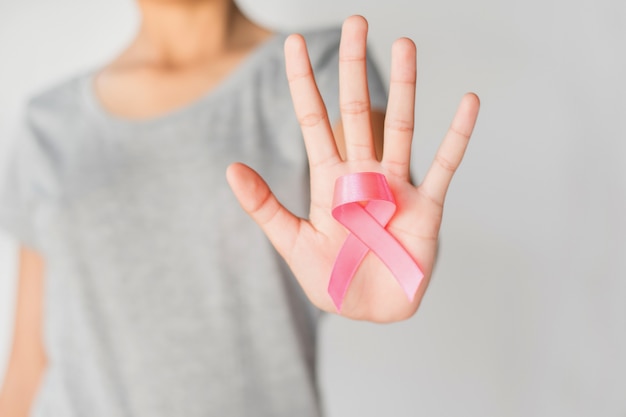 Woman hand holding pink ribbon breast cancer awareness. concept healthcare and medicine 