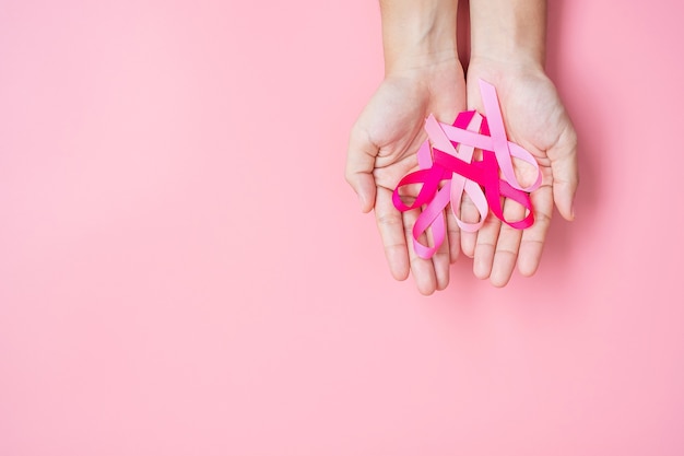 Woman hand holding Pink Ribbon on pink background