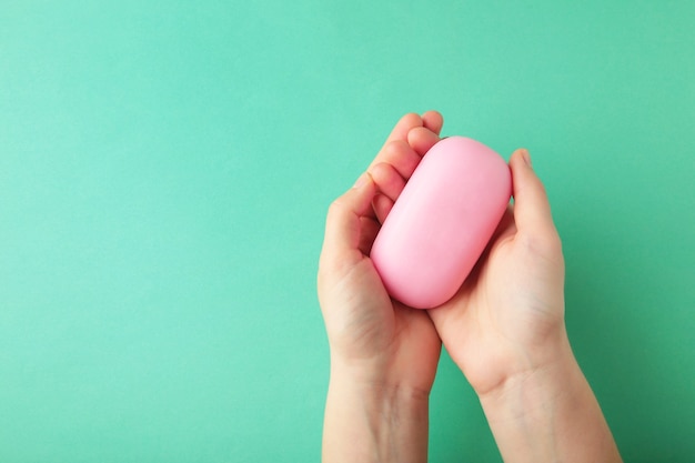 Woman hand holding a pink soap bar. top view