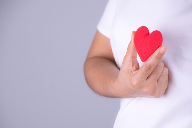 Foto mano della donna che tiene un cuore rosso. concetto di giornata mondiale del cuore.