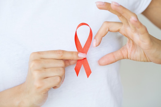 Woman hand holding red ribbon HIV, world AIDS day awareness ribbon.