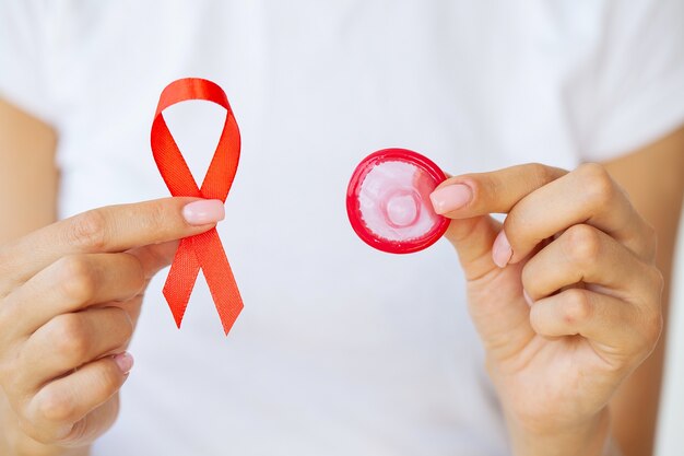 Woman hand holding red ribbon HIV, world AIDS day awareness ribbon.