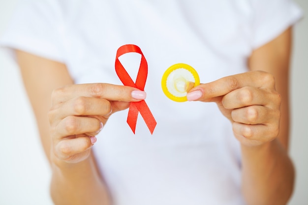 Woman hand holding red ribbon HIV, world AIDS day awareness ribbon.