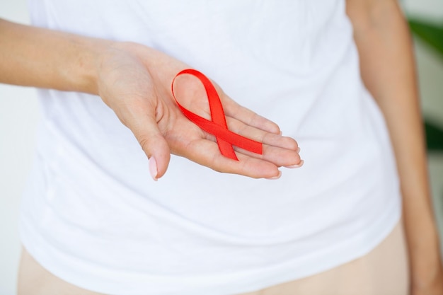 Woman hand holding red ribbon hiv world aids day awareness ribbon