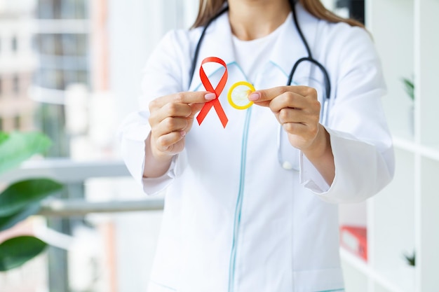 赤いリボンを持っている女性の手HIV世界エイズデー意識リボン